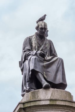 Glasgow, İskoçya, İngiltere - 17 Haziran 2012: Portre siyah bronz james Watt heykelin ışık mavi gökyüzü karşı George Square, taş kaide üzerine. Çok sayıda güvercin kaka ve iki kuş.