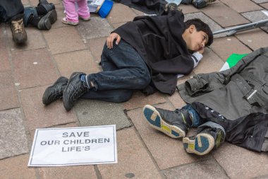 Glasgow, İskoçya, İngiltere - 17 Haziran 2012: Suriyeliler Bashar al-Assad'ın savaş suçları Donald Dewar heykel yakınındaki protesto. Tatlı çocuk düz yerde ölü taklidi.