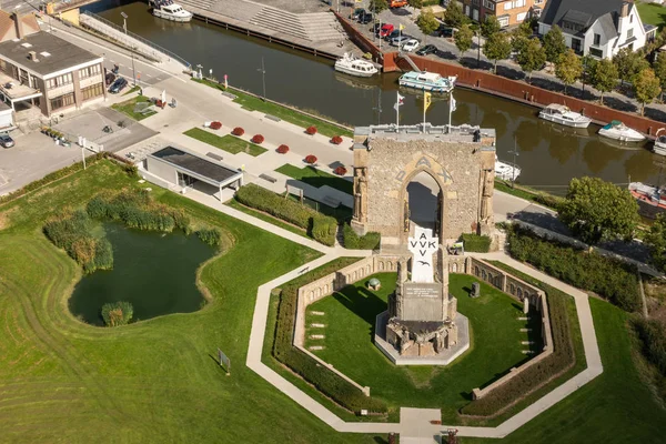 Diksmuide, Flanders, Belçika - 15 Eylül 2018: Havadan görünümü Pax kapısı ve crypt harabe arkada Ijzertoren düz Ijzer Nehri ile üzerinde. Beyaz haç, yeşil çim, bina ve karanlık su gemilerde AVV-Vvk sembolü. Ijzertoren tepesinden vurdu.
