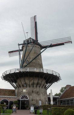 Sluis, Zeeland, Hollanda - 22 Eylül 2018: Sluis, Gümüş gökyüzü karşı ahşap dairesel geçit ile gri tuğla yapı yel değirmeni bir restoran, çay bahçesi ve pub olduğunu. Bazı yeşil bitki örtüsü.