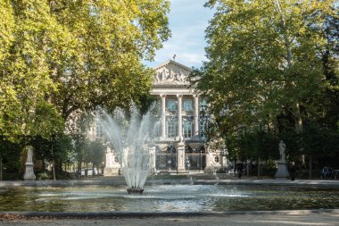 Brussels, Belçika - 26 Eylül 2018: Çeşme Brüksel Parkı'kısmen Belçika Parlamentosu cephe gizler. Yeşil yeşillik, heykeller ve insanlar bankta.