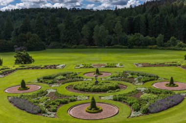 Holm Drumlanrig, İskoçya, İngiltere - 18 Haziran 2012: yeşil bahçe Drumlanrig Castle bulutlu gökyüzü altında. Koyu yeşil orman sınırları.