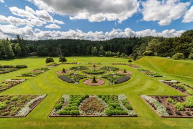 Holm Drumlanrig, İskoçya, İngiltere - 18 Haziran 2012: yeşil bahçe Drumlanrig Castle bulutlu gökyüzü altında. Koyu yeşil orman sınırları.