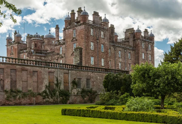 Holm Drumlanrig, İskoçya, İngiltere - 18 Haziran 2012: ücretsiz pembe kum taş Drumlanrig Castle bulutlu gökyüzü altında onun yüksek plato üzerinde duruyor. Geniş yeşil bahçe parçası.
