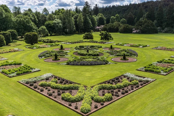 Holm Drumlanrig, İskoçya, İngiltere - 18 Haziran 2012: yeşil bahçe Drumlanrig Castle bulutlu gökyüzü altında. Koyu yeşil orman sınırları.