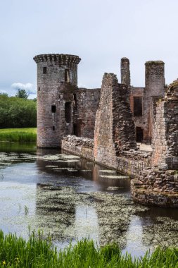 Shearington, İskoçya, İngiltere - 18 Haziran 2012: Closeup Güney tarafı yıkık üçgen kahverengi taş Caerlavarock Kalesi, tower adlı bakarken moated. Hendek yansımalar.