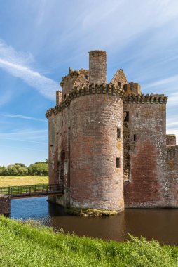 Shearington, İskoçya, İngiltere - 18 Haziran 2012: Giriş Kulesi ve hendek veya harap brown üzerinde köprü mavi gökyüzü altında Caerlavarock Kalesi taş. Yeşil otlar ve ağaçlar.