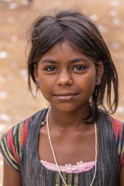 Angadihalli, Karnataka, Hindistan - 2 Kasım 2013: Genç kız siyah saçlı ve mavi Closeup onun kulakları gülümsüyor pimleri ve renkli gömlek ve elbise giyer. Bej renkli arka plan.