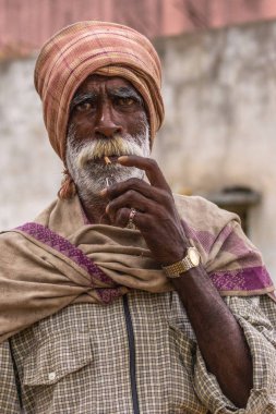 Angadihalli, Karnataka, Hindistan - 2 Kasım 2013: Beedi sigara kırmızı ve beyaz sakallı yaşlı bir adam portresi. Giyer türban, kareli gömlek ve omuz altın kol saati ile sarın.