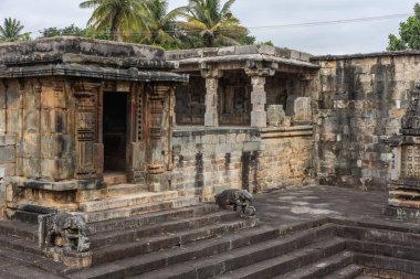 Belur, Karnataka, Hindistan - 2 Kasım 2013: Chennakeshava Tapınağı. Kahverengi taş harap tapınak gerekçesiyle su deposu için bitişik köşesinde. Fil heykeller ve yeşil ve palmiye ağaçlarının yukarıdaki karanlık adımları.