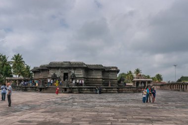 Belur, Karnataka, Hindistan - 2 Kasım 2013: Chennakeshava Tapınağı. Avlunun altında gri cennet koyu kahverengi taş Kesava tapınak inşa Doğu tarafında gösterir. Andal tapınak arkada. İnsanlar renk eklemek.