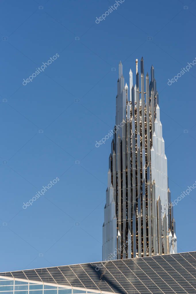 Garden Grove, California, USA - December 13, 2018: Crystal Christ Cathedral. Closeup of Crean Tower against blue sky. Roof of cathedral proper in front.