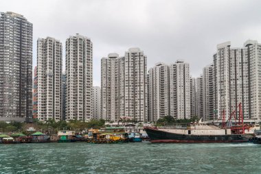 Hong Kong, Çin - 12 Mayıs 2010: Geniş vurdu. Siyah ve kırmızı balıkçı teknesi Harbor birçok uzun boylu apartman binaları ile kıyıya yanaştı. Yüzen ve ayırıcı olarak yeşil bitki örtüsü.