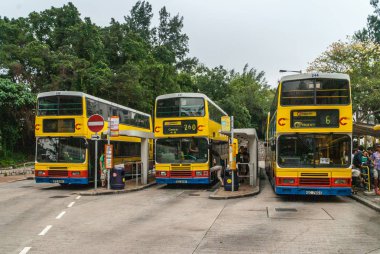 Hong Kong Adası, Çin - 12 Mayıs 2010: Üç sarı çift katlı ulaşımda otobüs durağında Stanley market yakınındaki. İnsanlar yatılı ve yeşil yaprakları arkada.