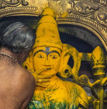 Belur, Karnataka, Hindistan - 2 Kasım 2013: Chennakeshava Tapınağı. Yarı çıplak rahip Andal tapınak Abisheka töreni sırasında zerdeçal tozu Devi Ranganayaki yüz yüz hatları tasarımlar. 