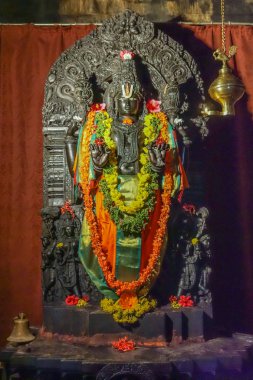 Belavadi, Karnataka, Hindistan - 2 Kasım 2013: Veera Narayana Tapınağı. Uzun boylu en önemli Narayana heykeli Vishnu tapınak içinde. Rengarenk çiçekler ve şeritler, karanlık metal heykel mahsup ile dekore edilmiş. 
