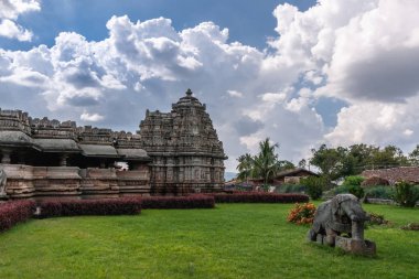 Belavadi, Karnataka, Hindistan - 2 Kasım 2013: Veera Narayana Tapınağı. Bahçede fil gri taş heykeli. Sanctuary ağır bulutları ile mavi gökyüzünün altında bir vimanam ile büyük yan.