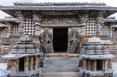Halebidu, Karnataka, Hindistan - 2 Kasım 2013: Hoysaleşvara Tapınağı, Shiva. İki koruyucu Dwarapalakas heykelleri ile ana giriş Mandapam için. Diğer heykeller. Gümüş gökyüzü altında.