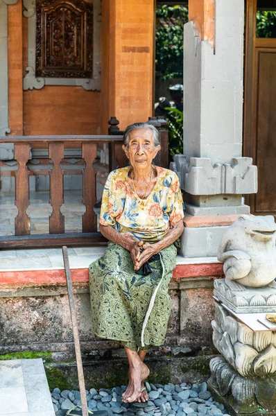 Yaşlı kadın aile bileşik, Dusun Ambeng de evin önünde oturur — Stok fotoğraf