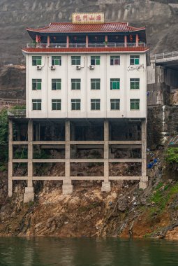 Wushan, Chongqing, Çin - 7 Mayıs 2010: Wu Gorge, Yangtze Nehri. Daning Nehri 'nin girişindeki kalelerin üzerine inşa edilmiş kırmızı Chinse tarzı çatısı olan beyaz otel-restoran..