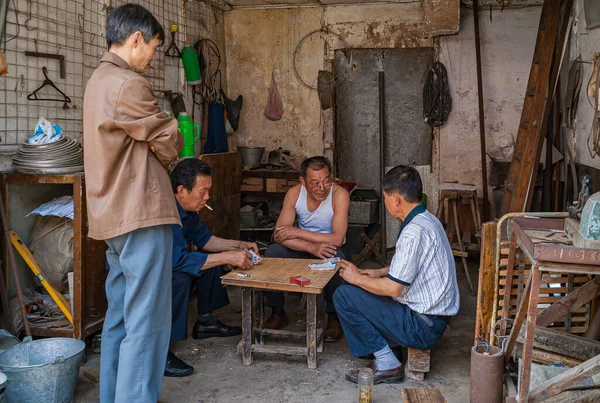 江蘇省通里2010年5月3日4人の労働者が茶色い木や金属製の道具がたくさんあるワークショップでカードゲームをする — ストック写真