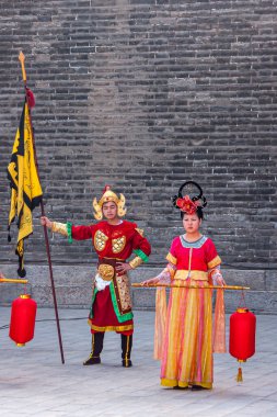 Xian, Çin - 30 Nisan 2010 Shuncheng Şehir Duvarı 'nın Kuzey Kapısı' nın karşılama töreni. Kırmızı fenerli kız dansçı ve sarı bayrak taşıyan bekçi. Arkaplan olarak gri taş duvar. 