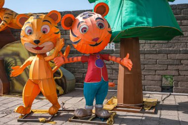 Xian, Çin - 30 Nisan 2010 Huancheng Duvarı 'nın kuzey kapısı. Kaplan yılı gösterisi. Arkaplanı yeşil ve kahverengi olan iki dev sahte turuncu kaplan bebeği..