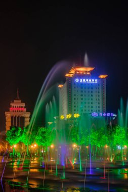 Xian, Çin - 1 Mayıs 2010: Kara Gece Sahnesi. Şehir merkezindeki HNA Otel 'i aydınlattı. Renkli çeşmeler ve yeşil ışıklı ağaçlar arasında görüldü..