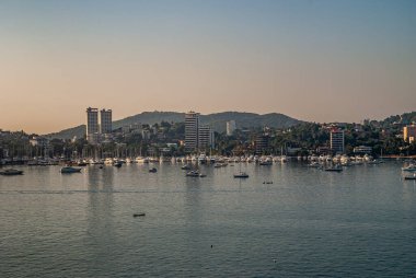 Acapulco, Meksika - 25 Kasım 2008: Yat limanlı Twilihgt üzerinde yüksek binalar ve yüksek binalar. Yeşil tepelerin arkaplanı, açık mavi gökyüzünün altında.