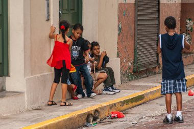 Panama City, Panama - 30 Kasım 2008: 6 genç çocuk, erkek ve kız çocuğu, sokağın önünde, çöplerle birlikte. Bej duvar, yeşil kapı, ve koyu metal garaj kapısı..