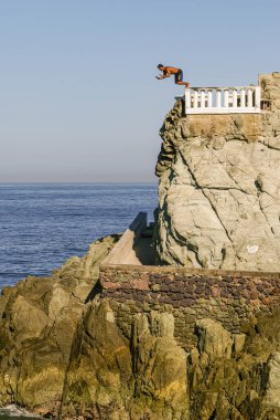 Mazatlan, Meksika - 23 Nisan 2008: Adam El Clavadista 'dan Pasifik Okyanusu' na daldı. Kahverengi kayalar açık mavi gökyüzünün altında, daha koyu deniz suyunun altında.