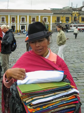 Quito, Ekvador - 2 Aralık 2008: Şehir merkezi tarihi. Her renkte tekstil eşarpları tanıtan yerli kadın ambulans tedarikçisine yakın çekim. Çevredeki diğer insanlar.