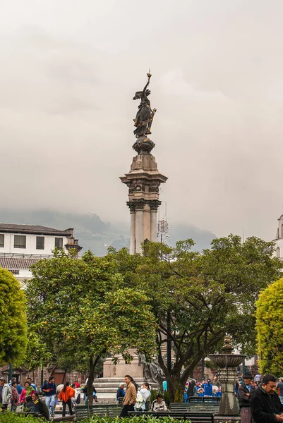 エクアドル 2008年12月2日 歴史的なダウンタウン プラザ グランデ 独立記念碑 または8月10日の英雄 灰色の茶色の雨の空の下で緑の葉の上にそびえる 周りの歩行者 — ストック写真