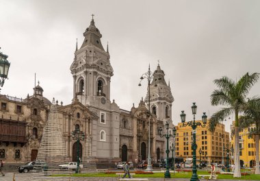 Lima, Peru - 4 Aralık 2008: Havari Aziz John Bazilika Katedrali gümüş gökyüzünün altındaki yeşil Plaza Belediye Başkanı 'nın arkasındaki gri taş binadır. Sarı binalar yan tarafta. Noel süslemeleri ve yayalar.
