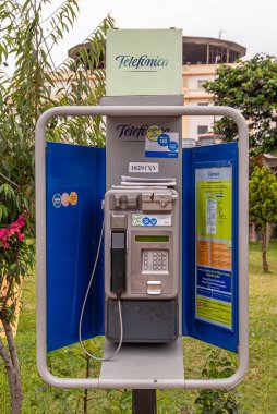 Lima, Peru - 4 Aralık 2008: Telefica devlet para idaresi altındaki telefon kulübesinin kapatılması. Metal gri ve mavi, yeşil çimenler ve bitkilerle çevrili. Biraz kırmızı çiçek ve gümüş gökyüzü.