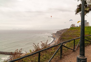Miraflores, Peru - 4 Aralık 2008: Gri Pasifik Okyanusu üzerindeki sisli gümüş gökyüzünde paraşütle atlayan sahil ve uçurumlar. Yeşil yaprak