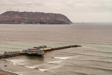 Miraflores, Peru - 4 Aralık 2008: Yerel iskele, ufukta dağ ve kıyı şeridi bulunan yeşil-gri Pasifik Okyanusuna kadar uzanır..