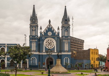Lima, Peru - 4 Aralık 2008: Önünde yeşil yapraklı gümüş-kahverengi bulutların altında La Recoleta Kilisesi 'nin beyaz desenli mavi cephesi. Etrafa bakıyorum. Özgürlük Heykeli.
