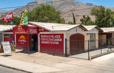 Vicuna, Şili - 7 Aralık 2008: Renkli bayraklarla cadde boyunca Minimarket Market 'in ön cephesi ve binası. Arkaplan kuru dağ ve mavi gökyüzü. Biraz yeşil yaprak..