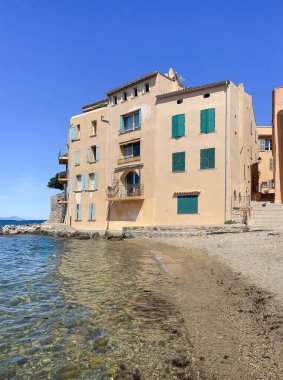 Saint Tropez, France - July 13, 2024: Downtown scenery. Residential building on East side of Plage de la Glaye. Pebbles on beach. Cruise ship on Gulf water, all under blue sky