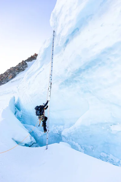 Alpinista scalatore scalare scaletta sul ghiaccio crepaccio . — Foto Stock