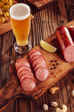 Bir bardak bira, zeytin, kestane ve şam fıstığı ile dilimlenmiş füme salam.