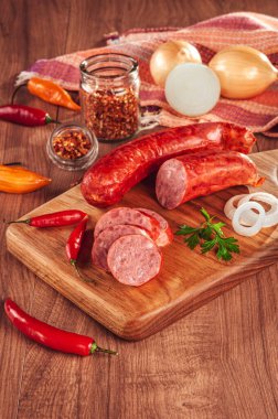 Ahşap bir masada, içinde malzemeler olan dilimlenmiş sosis.