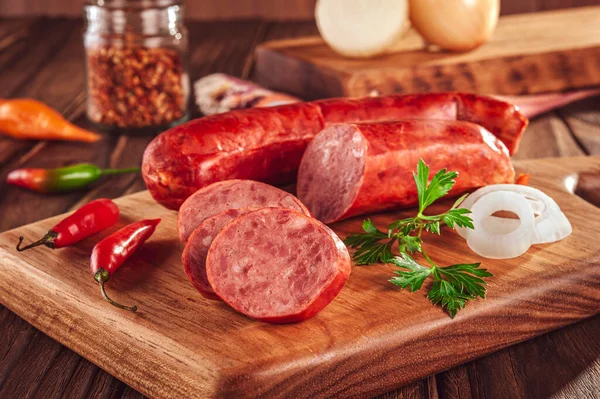 Ahşap bir masada, içinde malzemeler olan dilimlenmiş sosis.