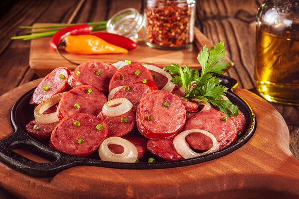 Sliced smoked calabrese sausage with onion and calabrese pepper in a wooden background - Brazilian appetizer close-up