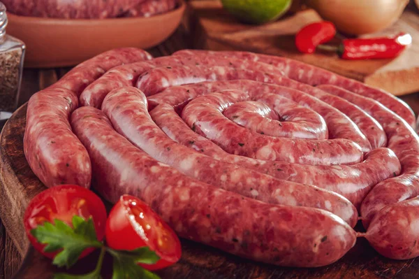 Tahtadaki çiğ Brezilya sosislerinde Linguica churrasco malzemeleri var.