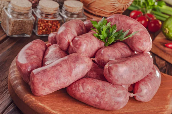 Tahtadaki çiğ Brezilya sosislerinde Linguica churrasco malzemeleri var.