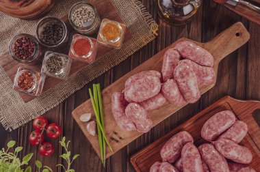 Tahtadaki çiğ Brezilya sosislerinde Linguica churrasco malzemeleri var.