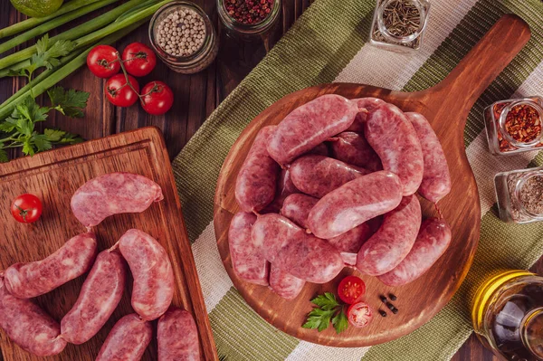 Tahtadaki çiğ Brezilya sosislerinde Linguica churrasco malzemeleri var.