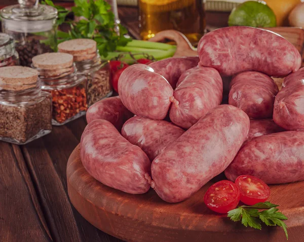 Tahtadaki çiğ Brezilya sosislerinde Linguica churrasco malzemeleri var.